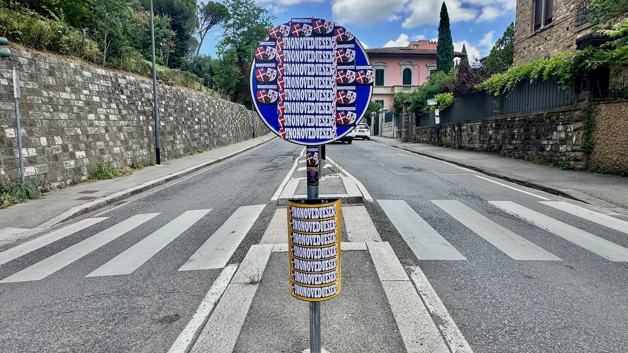 Il cartello stradale nascosto da adesivi di ultras viola in via di San Domenico a Firenze